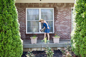 A man watering plants displayed in a patio in Houston, TX